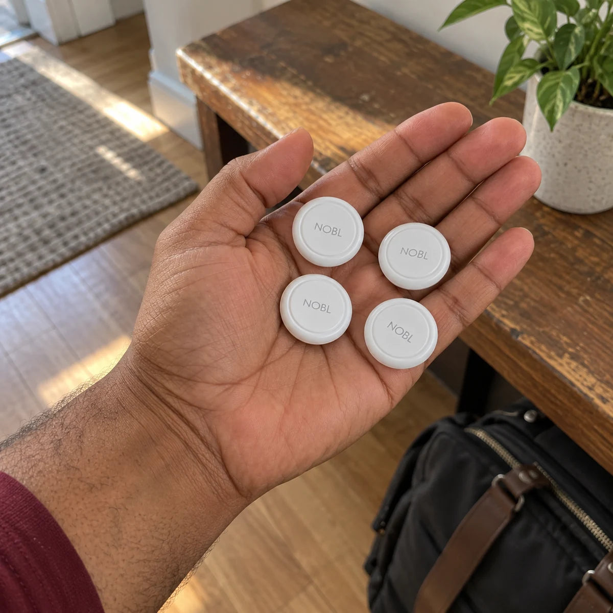 Four NOBL Air trackers in a man's palm at home